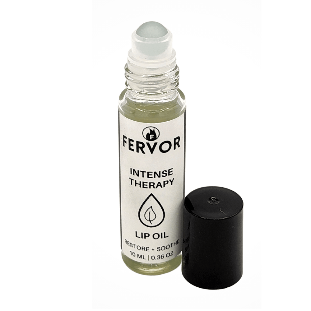 Fervor Candle Company Intensive Therapy Lip Oil product photo. Round clear glass rollerball with white and black label, and black twist on cap, filled with clear liquid product.