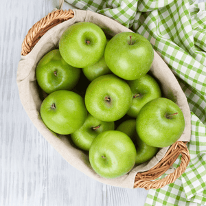 
                  
                    Fervor Candle Company Juicy Green Apple Room & Linen Mist scent inspiration photo. A white-washed wooden table with green and white checkered cloth displaying a linen-lined wicker basket full of shiny green apples.
                  
                