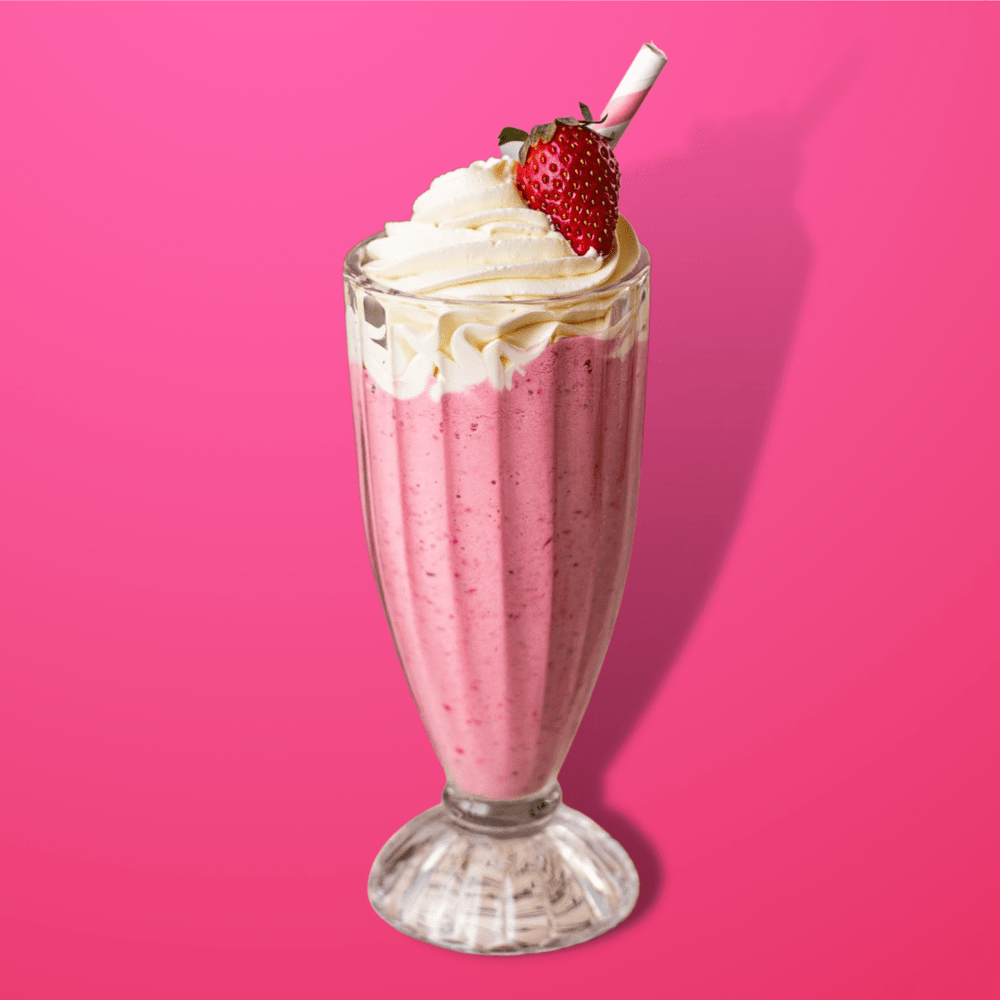 Strawberry Milkshake Skin Soothing Bubble Bath by Fervor Candle Company scent inspiration photo. Picture of a pink strawberry milkshake with whipped cream and strawberry garnish in an old-fashioned ice cream shop milkshake glass against a vibrant pink background.